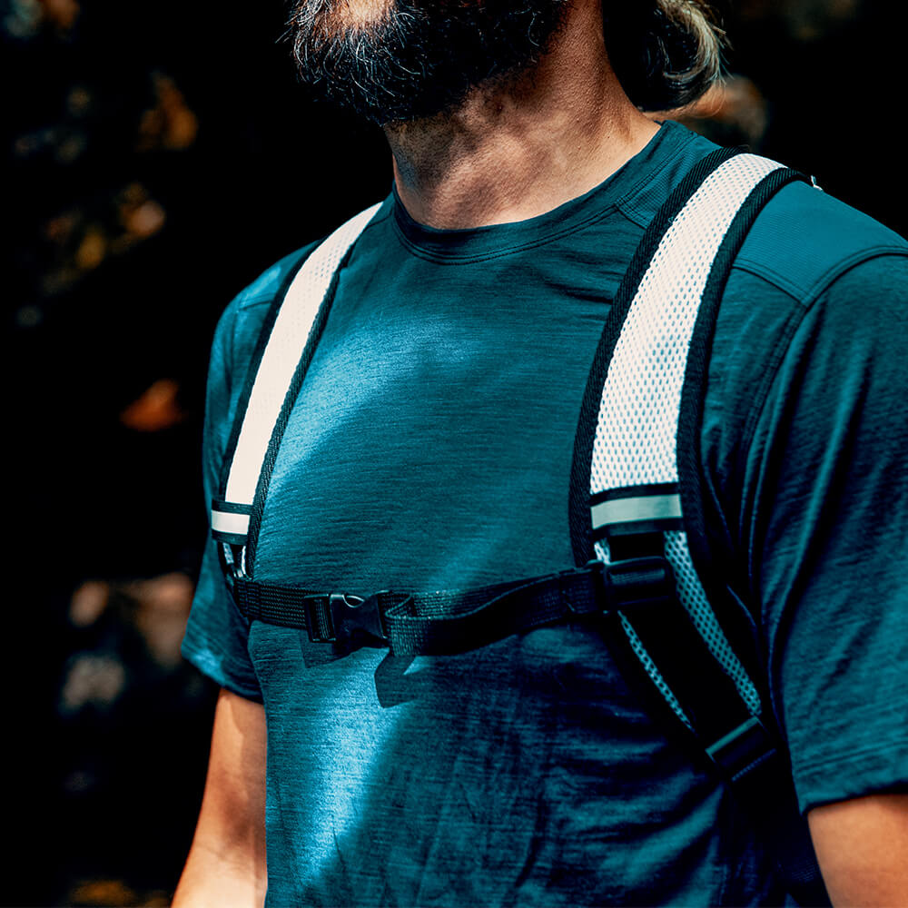 A young outdoor enthusiast wears a white comfort strap Vayska hydration pack in the outdoors.